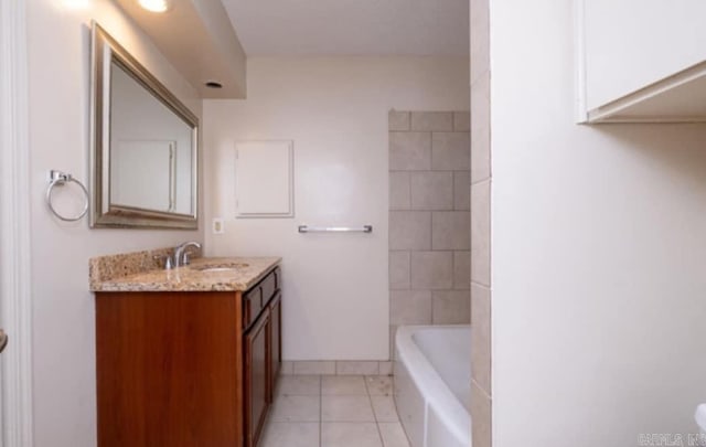 bathroom featuring baseboards, a tub to relax in, vanity, and tile patterned floors
