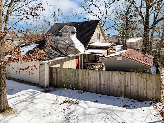 view of snow covered exterior with a garage and fence