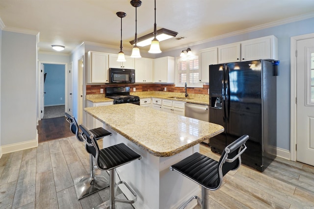 kitchen with a breakfast bar, a center island, black appliances, pendant lighting, and a sink