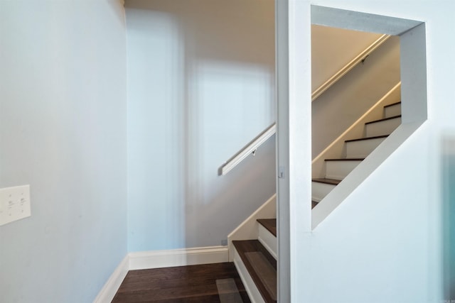 staircase featuring baseboards and wood finished floors