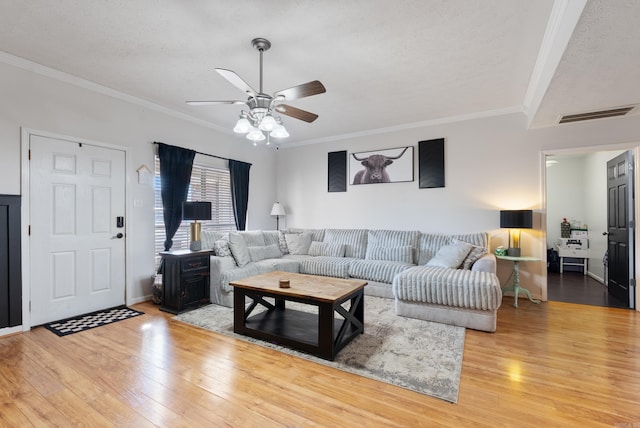 living area with hardwood / wood-style flooring, crown molding, visible vents, and ceiling fan