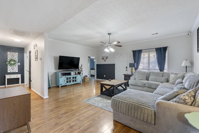 living room featuring visible vents, light wood-style flooring, and ornamental molding