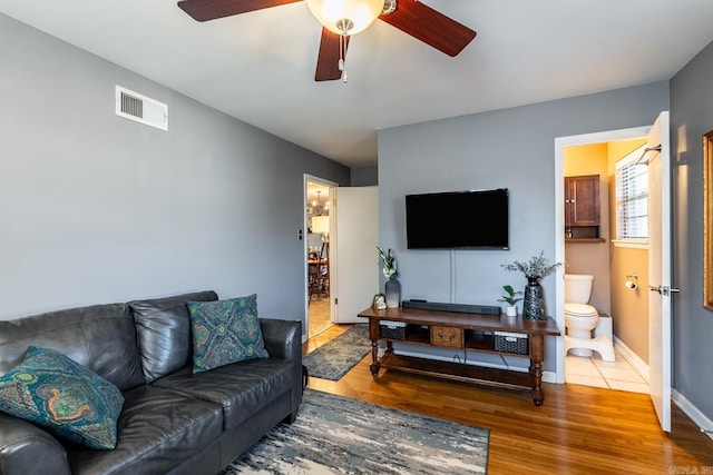 living area with a ceiling fan, baseboards, visible vents, and wood finished floors