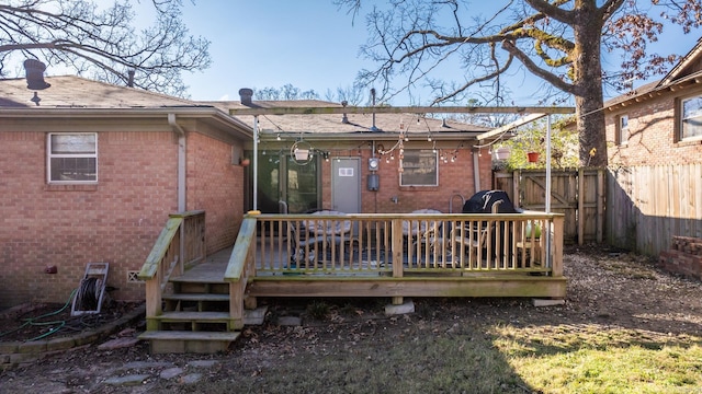 back of house featuring a chimney, brick siding, a deck, and a fenced backyard