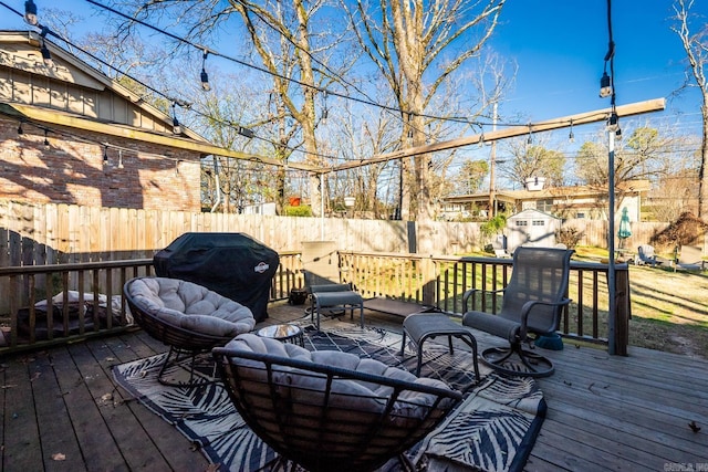 wooden deck with a fenced backyard and a grill