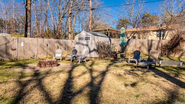 view of yard with an outdoor fire pit, a fenced backyard, an outdoor structure, and a shed