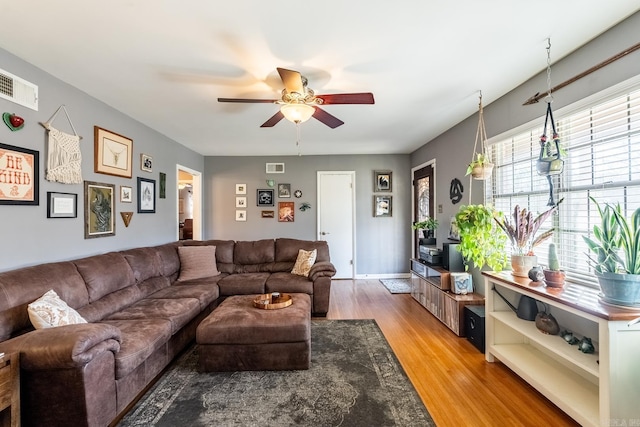 living room with wood finished floors, visible vents, and a ceiling fan