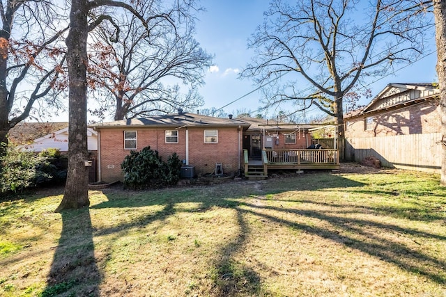 back of house with brick siding, fence, a lawn, and a wooden deck