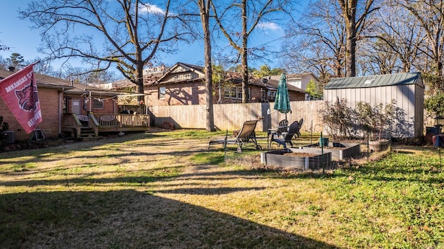 view of yard featuring a deck, an outbuilding, a storage shed, fence, and a vegetable garden