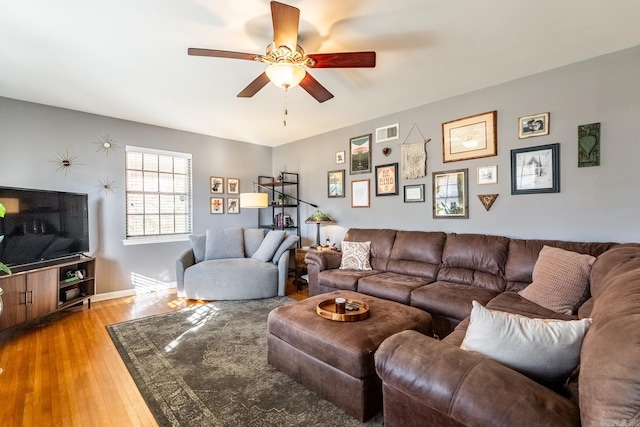 living area with visible vents, baseboards, light wood-style flooring, and a ceiling fan