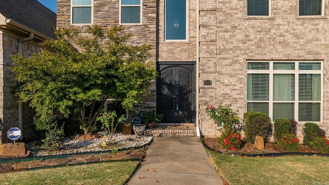 entrance to property with brick siding and a yard