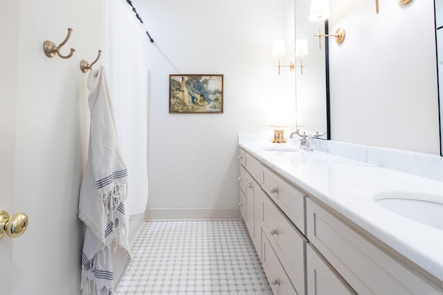 bathroom with double vanity, baseboards, and a sink