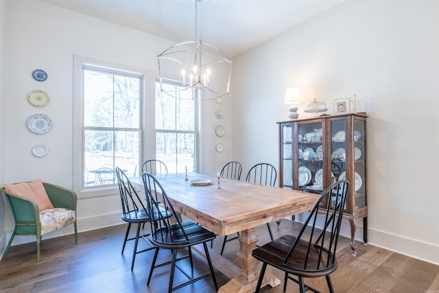 dining space with baseboards, a healthy amount of sunlight, dark wood finished floors, and an inviting chandelier