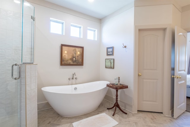 full bath featuring a freestanding tub, a shower stall, and baseboards