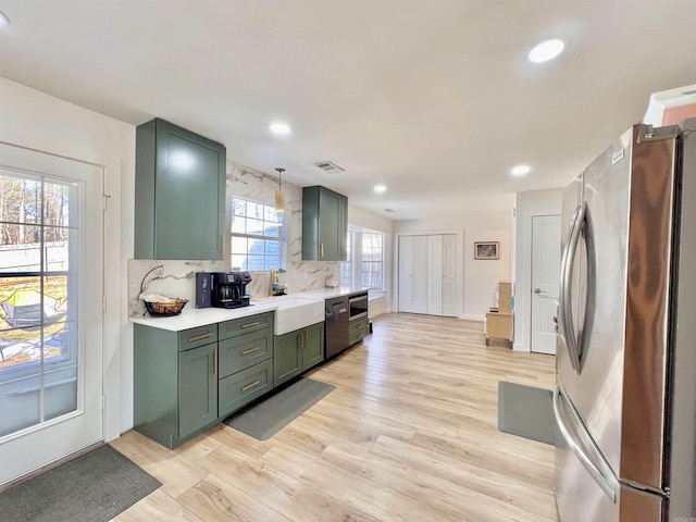 kitchen featuring light wood-style floors, light countertops, appliances with stainless steel finishes, decorative light fixtures, and green cabinetry