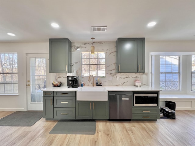 kitchen with stainless steel appliances, a sink, visible vents, light countertops, and pendant lighting