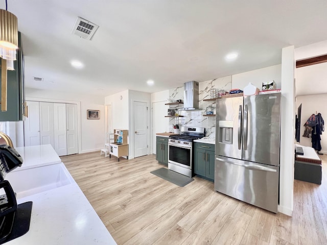 kitchen with open shelves, visible vents, light countertops, appliances with stainless steel finishes, and wall chimney range hood