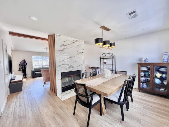 dining area featuring visible vents, baseboards, light wood-style flooring, a premium fireplace, and recessed lighting