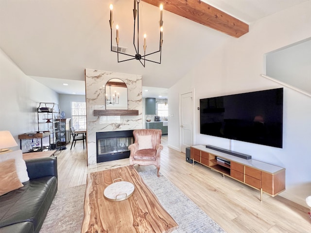 living area with visible vents, wood finished floors, a chandelier, beam ceiling, and a high end fireplace