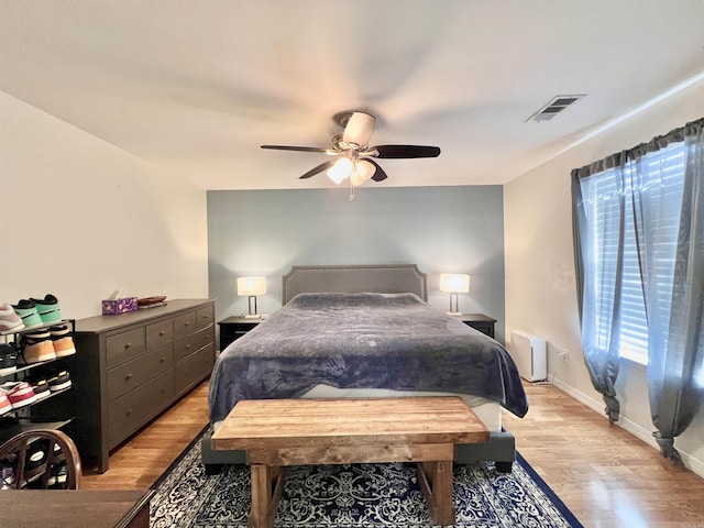 bedroom featuring light wood finished floors, ceiling fan, visible vents, and baseboards