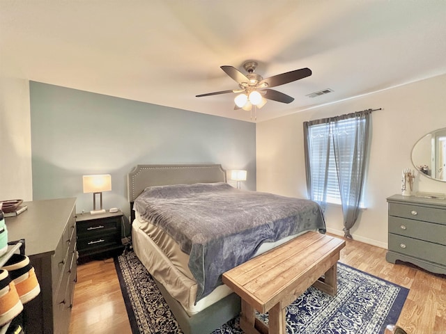 bedroom with light wood-type flooring, ceiling fan, visible vents, and baseboards