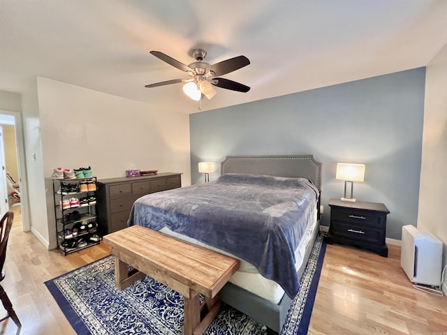 bedroom with ceiling fan, light wood-style flooring, and baseboards