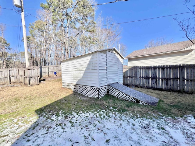 snow covered structure featuring a yard, a fenced backyard, an outdoor structure, and a shed