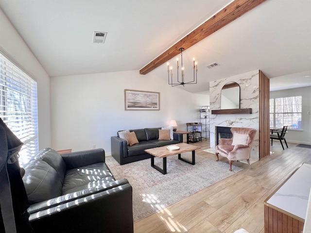 living room with visible vents, lofted ceiling with beams, an inviting chandelier, light wood-style floors, and a fireplace