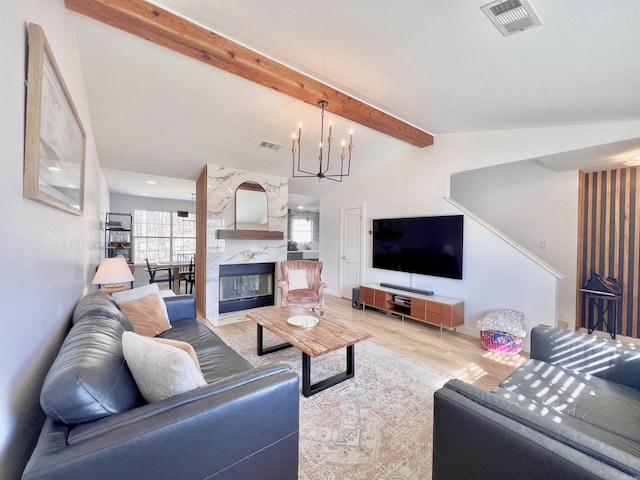 living room featuring vaulted ceiling with beams, a notable chandelier, a fireplace, wood finished floors, and visible vents