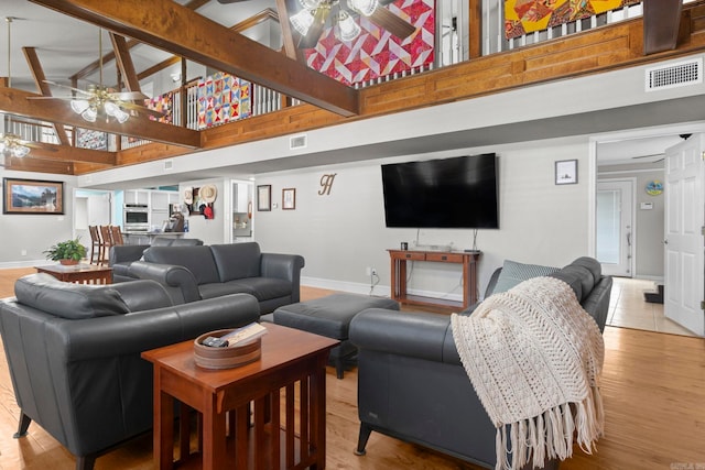 living area featuring light wood-style flooring, a high ceiling, and a ceiling fan