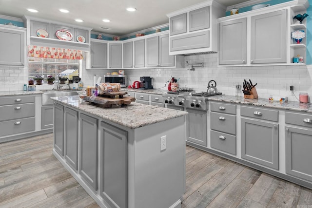 kitchen with open shelves, light wood finished floors, gray cabinets, and a center island