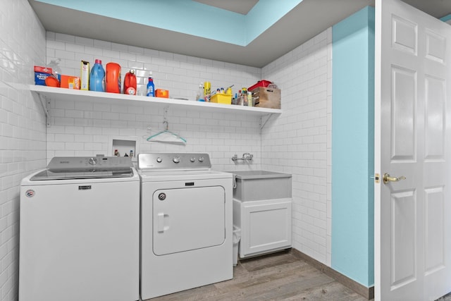 laundry room with separate washer and dryer, light wood-style flooring, cabinet space, and tile walls