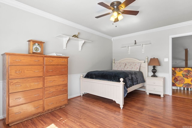 bedroom with dark wood-style floors, wainscoting, a ceiling fan, and crown molding