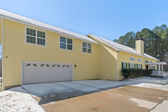 view of front facade with driveway, a garage, and a chimney