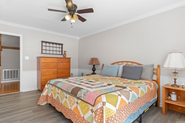 bedroom featuring ornamental molding, a wainscoted wall, visible vents, and dark wood finished floors