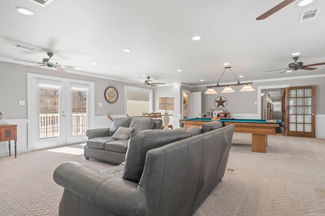 living area with light carpet, wainscoting, visible vents, and french doors