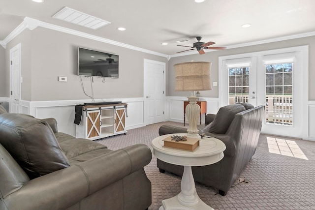 living room with light carpet, french doors, a wainscoted wall, and ornamental molding