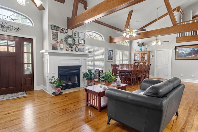 living area with high vaulted ceiling, beam ceiling, baseboards, and wood finished floors