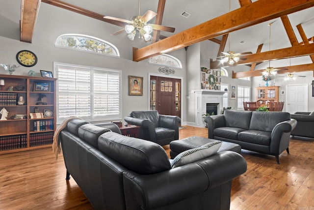 living room featuring high vaulted ceiling, a fireplace, wood finished floors, visible vents, and beam ceiling