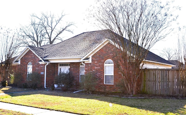 view of front facade featuring a front yard, fence, and brick siding