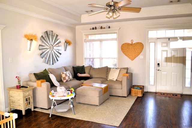 living area with dark wood-style floors, a tray ceiling, visible vents, and crown molding