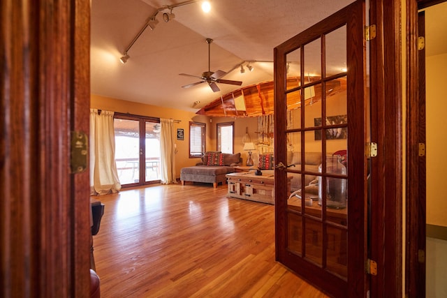 interior space with a ceiling fan, vaulted ceiling, and light wood finished floors