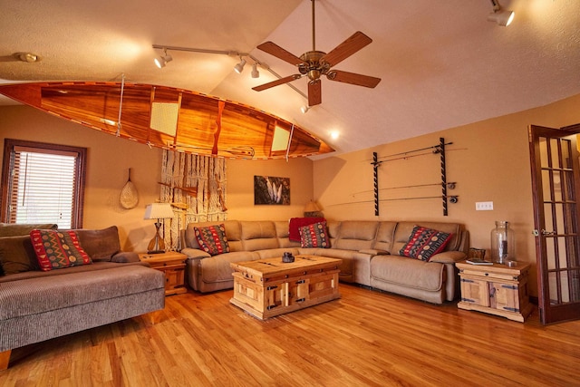 living room featuring light wood-type flooring, rail lighting, ceiling fan, and lofted ceiling