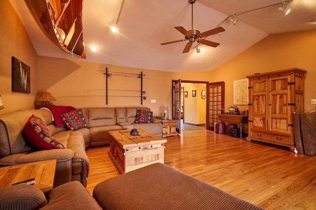 living room featuring light wood-type flooring, rail lighting, vaulted ceiling, and ceiling fan