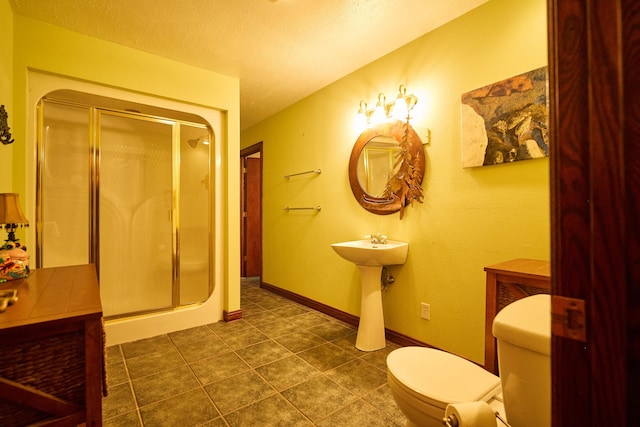 bathroom with a stall shower, baseboards, toilet, tile patterned floors, and a textured ceiling