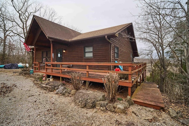 view of property exterior with a shingled roof and a wooden deck