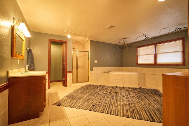 bathroom with a stall shower, tile patterned flooring, a textured ceiling, and a bath