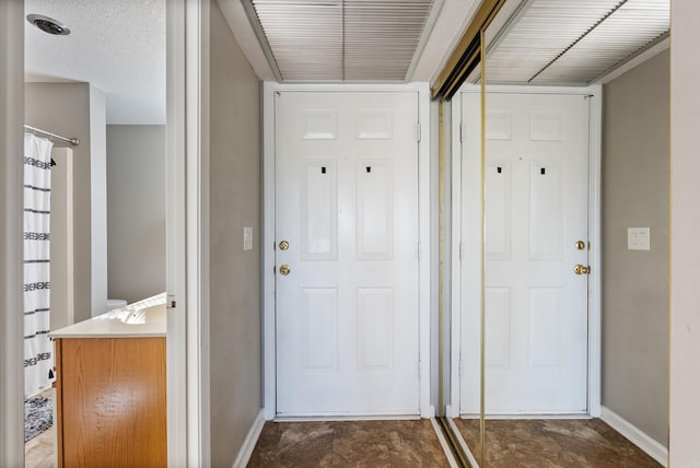 doorway to outside featuring a textured ceiling and baseboards