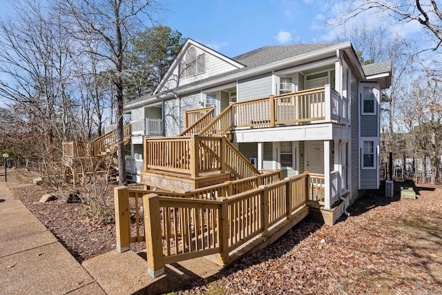 view of front of property featuring a balcony, a shingled roof, and cooling unit