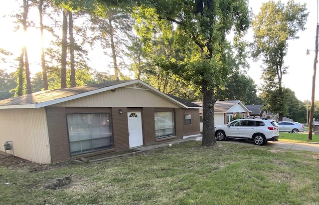 view of front facade with driveway, a front lawn, and brick siding